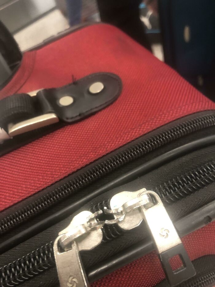 Red suitcase with broken zipper lock, highlighting an airline baggage fail.