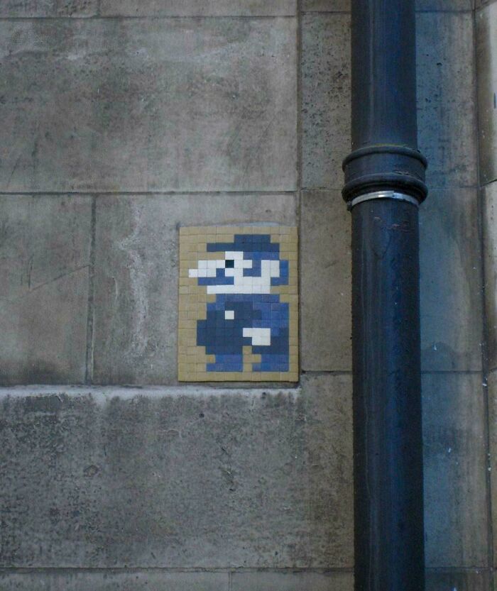 Pixelated street art resembling a video game character on a concrete wall, illustrating chaotic good morally grey acts.