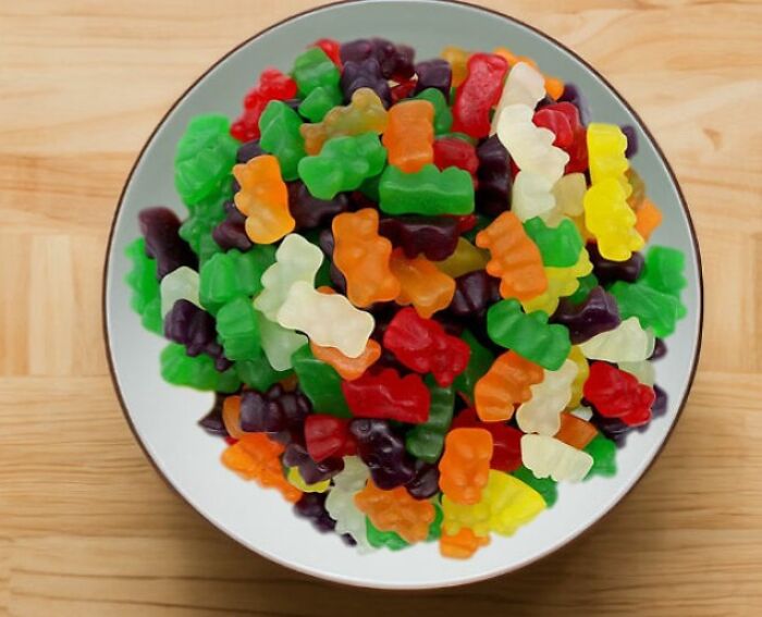 A bowl of colorful gummy bears on a wooden table, illustrating Amazon masterpieces.