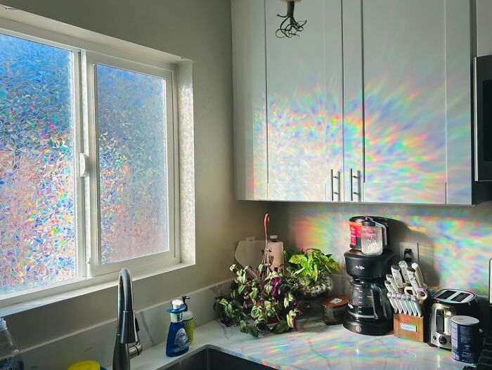 Prismatic sunlight creates rainbow effects on a kitchen wall, influenced by TikTok-inspired window film.