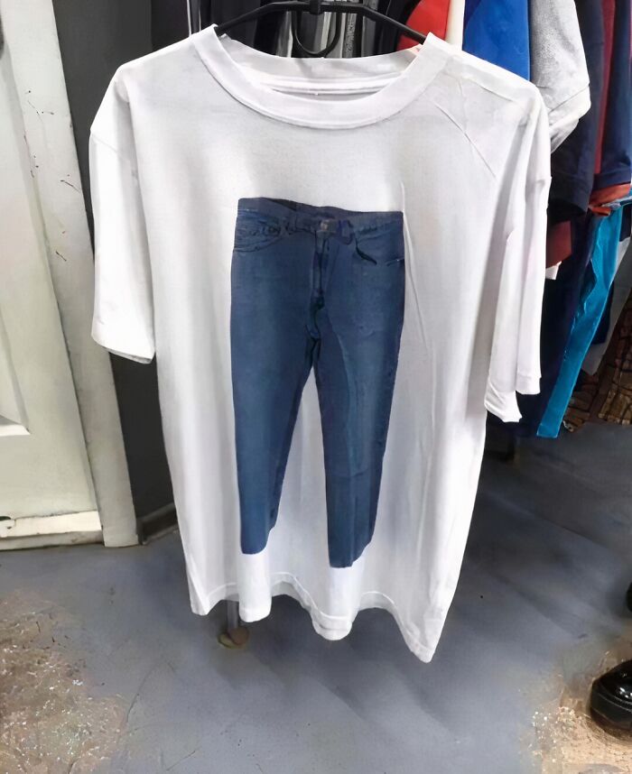 White t-shirt featuring an image of blue jeans hanging on a rack. Chaotic fashion statement.