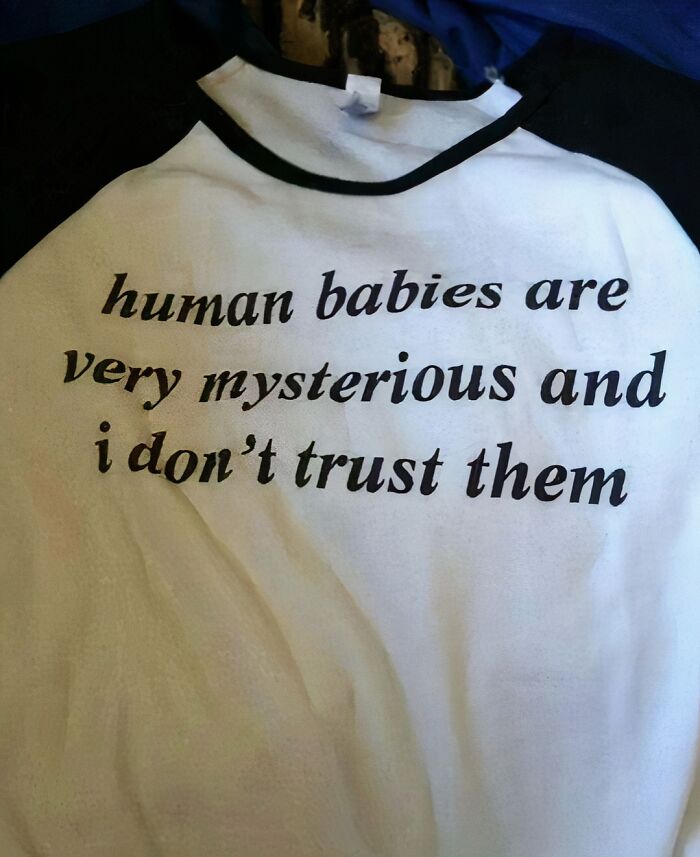 T-shirt with text: "human babies are very mysterious and i don't trust them," capturing chaotic humor.