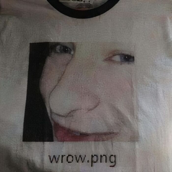 Close-up of a face printed on a chaotic T-shirt with "wrow.png" text.