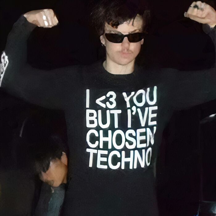 Person flexing in sunglasses, wearing a chaotic T-shirt with "I 