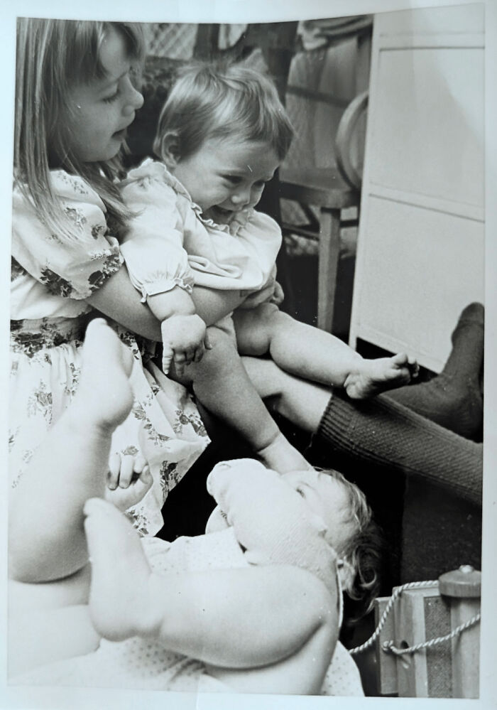 Black and white candid photograph of young children playing indoors, capturing genuine glimpses into the past moments.