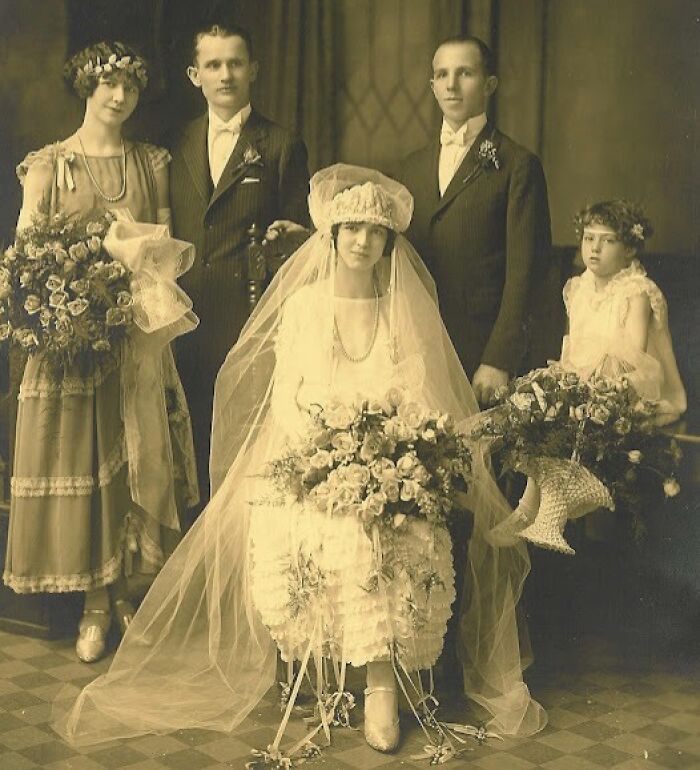 Vintage wedding scene with bride, groom, and attendants from 50-100 years ago showcasing historic fashion and style.