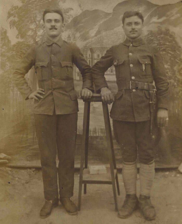 Two men in early 20th-century military uniforms stand by a stool, exemplifying historical world changes.