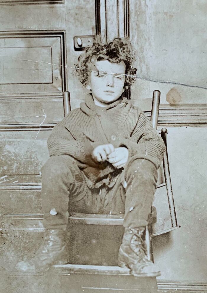 Young child in vintage attire sitting on steps, reflecting rare historical fashion changes.