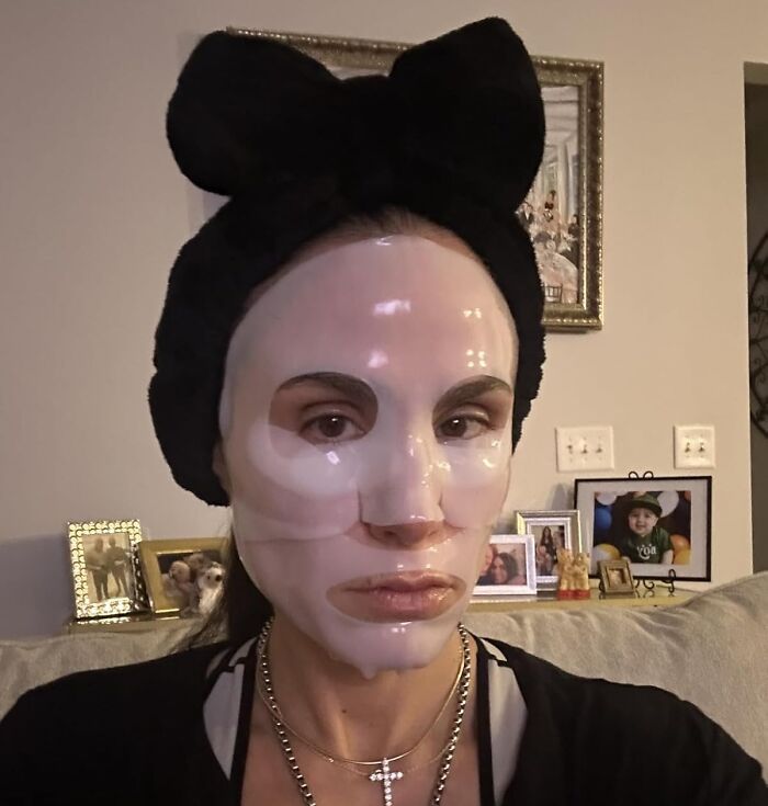 Woman wearing a sheet mask at home, showing real beauty product usage.