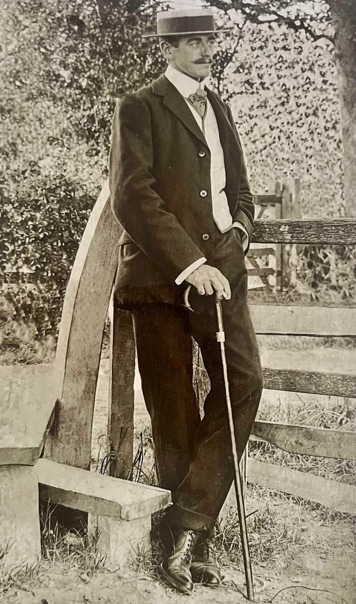 Dapper man in early 1900s attire with a cane, showcasing rare historical fashion from a century ago.