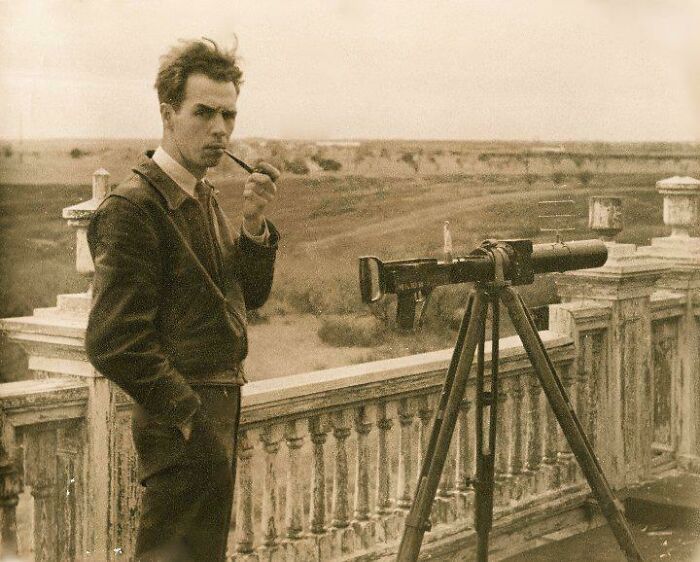 Vintage photo of a man with a pipe beside an old telescope on a balcony, illustrating historical changes.