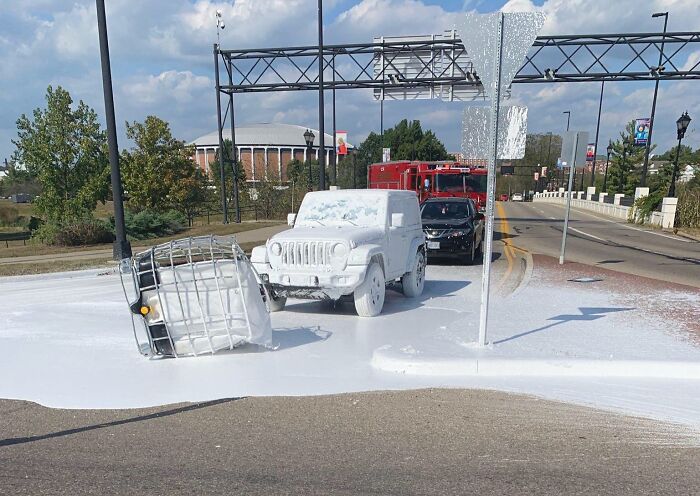 Jeep covered in white paint after an accident on a road, highlighting an expensive mishap.