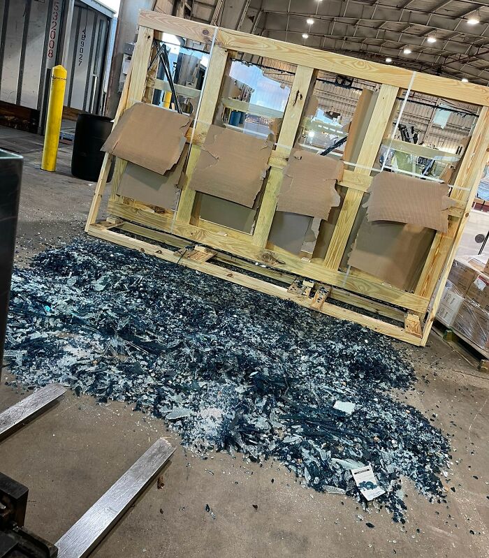 Shattered glass in a warehouse after an expensive accident, wooden frame still standing.