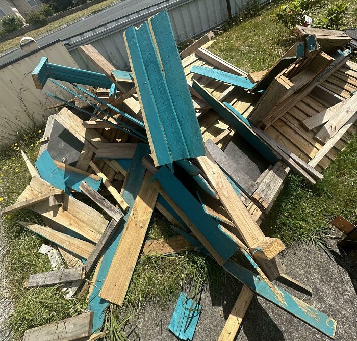 Broken wooden structure in backyard after an expensive accident, with scattered blue and natural planks.