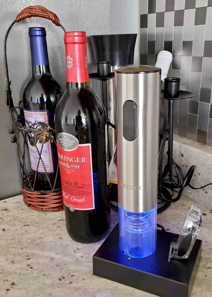 Electric wine opener beside bottles on a kitchen counter showcasing ultra-specific product functionality.