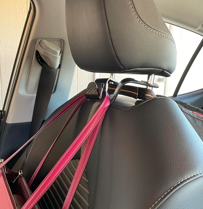 Car headrest hook holding a pink bag, showcasing an ultra-specific product solution for organizing vehicle space.