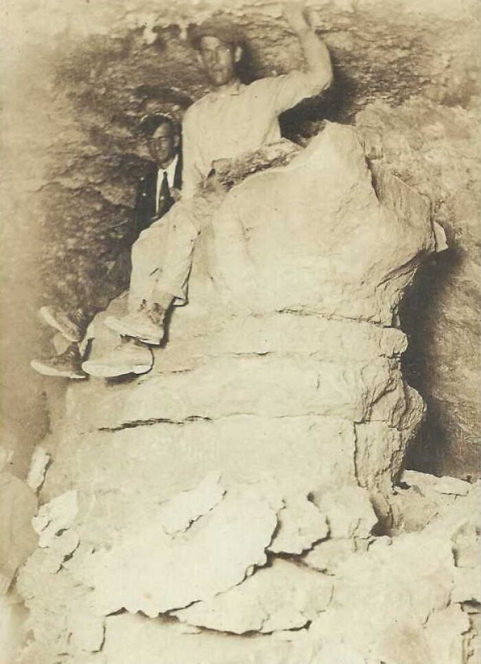Two men pose in a cave, one sitting on a rock formation, illustrating rare historical moments from decades ago.
