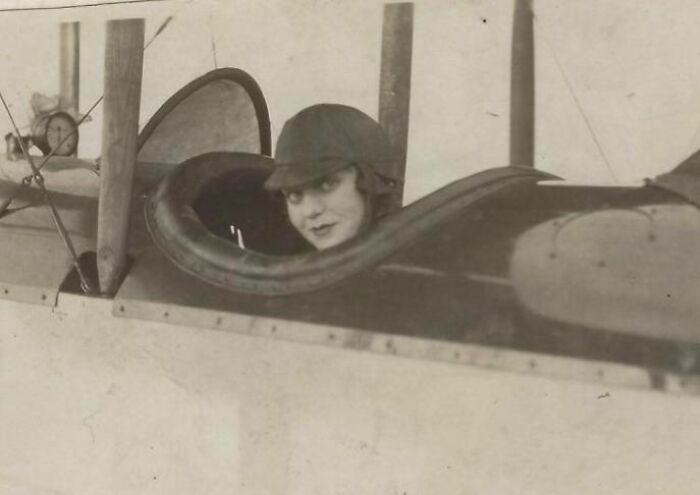 Young woman pilots a vintage airplane, illustrating rare historical changes from 50-100 years ago.