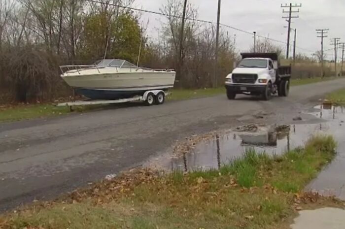 Boat on a trailer beside a road with a truck, found through Google Earth in a strange, unexpected location.