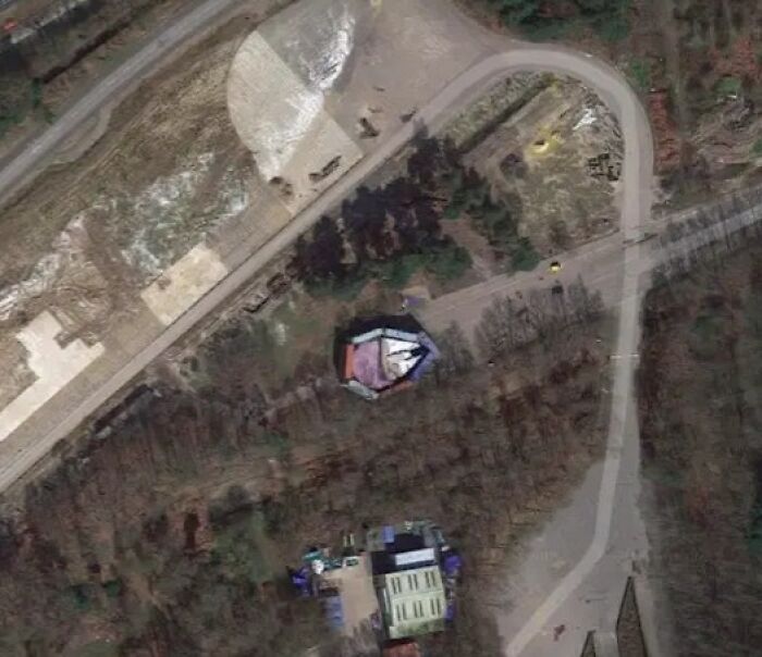 Strange Google Earth find with a face-like shape and winding paths near a forested area.