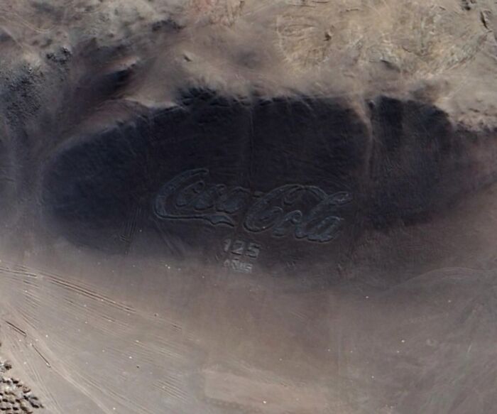 Aerial view of a large Coca-Cola logo etched into the desert, a strange find on Google Earth.