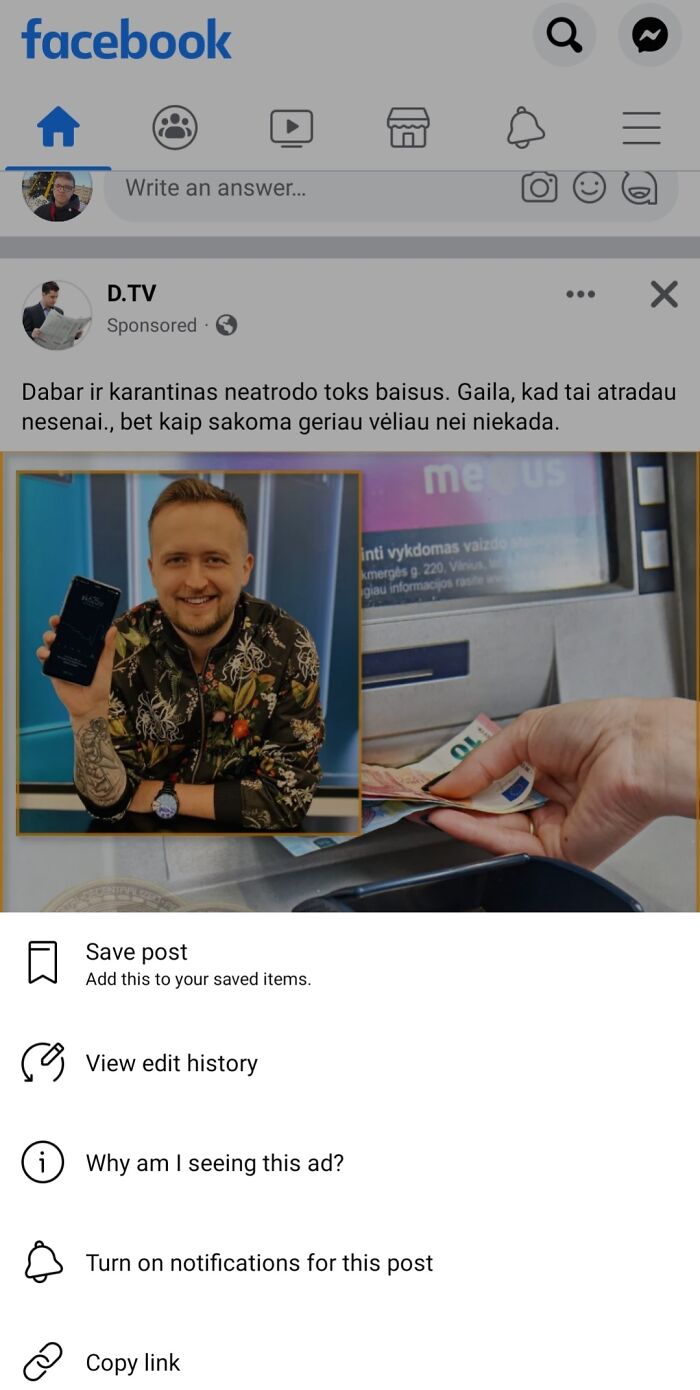 Man holding smartphone with ATM cash withdrawal in background, highlighting shameless scams.