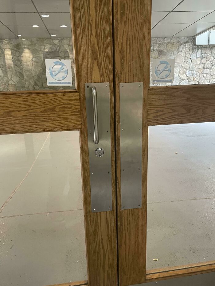 Wooden door with two metal handles facing the same direction, illustrating a design fail.