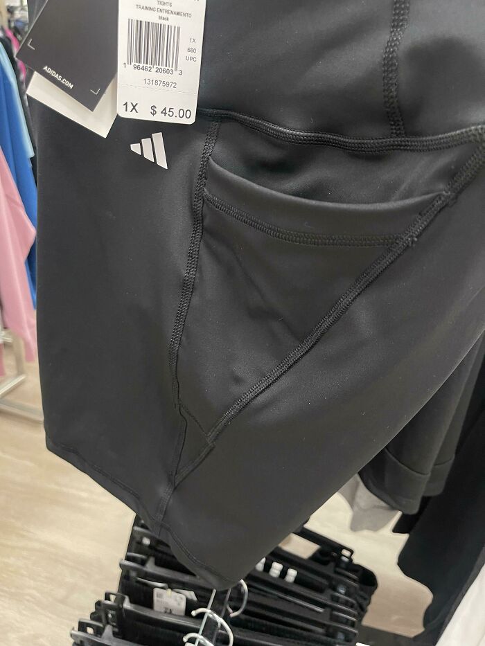 Black shorts with a poorly sewn pocket seam on display, showcasing a design fail in a retail store setting.