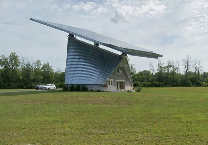 Casa con diseño arquitectónico inusual, techo desproporcionado en campo abierto.