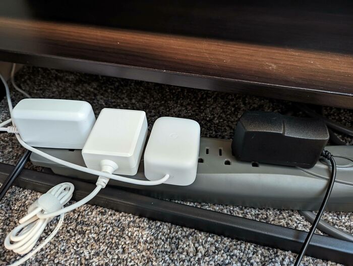 Design fail showing a power strip overloaded with mismatched adapters, highlighting poor setup planning.
