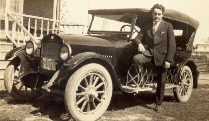 Man in a suit posing with a vintage car, illustrating rare photos from 50-100 years ago showing world change.