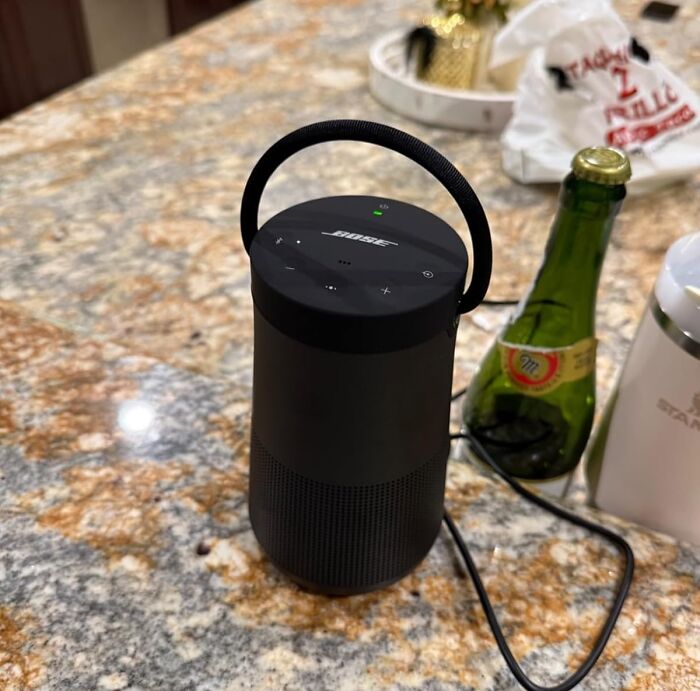 Black Bose speaker on granite countertop, part of Amazon spring deals, next to a green bottle and a white mug.