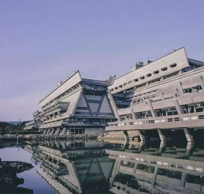Brutalist concrete buildings with sharp angles near water, evoking an evil aura like supervillain headquarters.