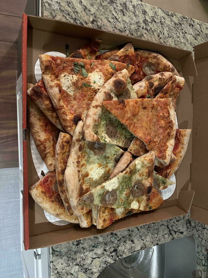 A box filled with various slices of leftover pizza, a common dumpster diving treasure in neighborhoods.