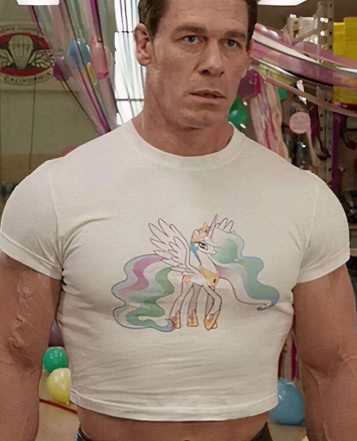 Man wearing a snug, whimsical unicorn T-shirt in a colorful room, showcasing chaotic fashion choice.