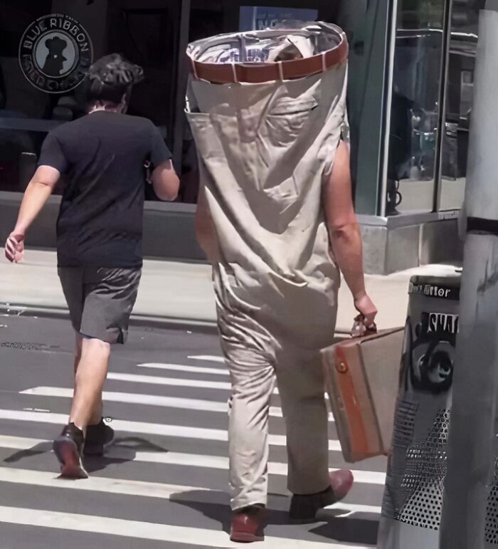 Person in oversized pants costume walking alongside another person on a city street. Chaotic T-shirt humor.