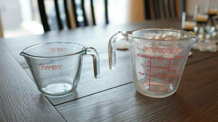 Two Pyrex measuring cups on a wooden table, exemplifying a Buy It For Life purchase that didn't disappoint.