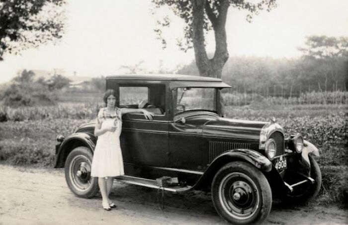 Vintage car with a woman from the past, illustrating how the world has changed over time.