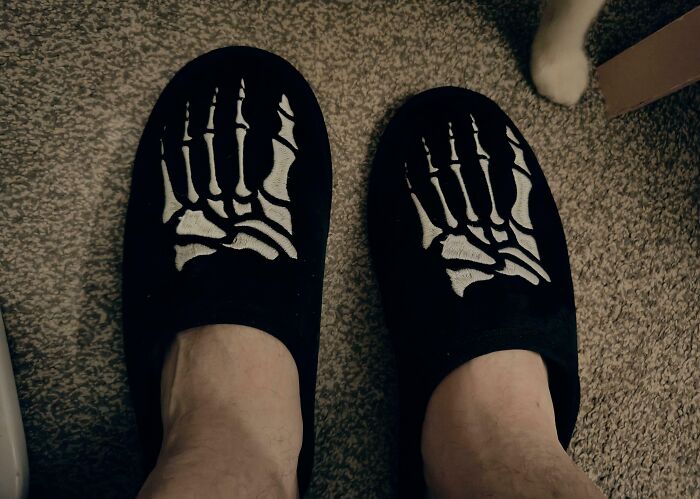 Design fails: slippers with mismatched skeleton feet print on a carpeted floor.
