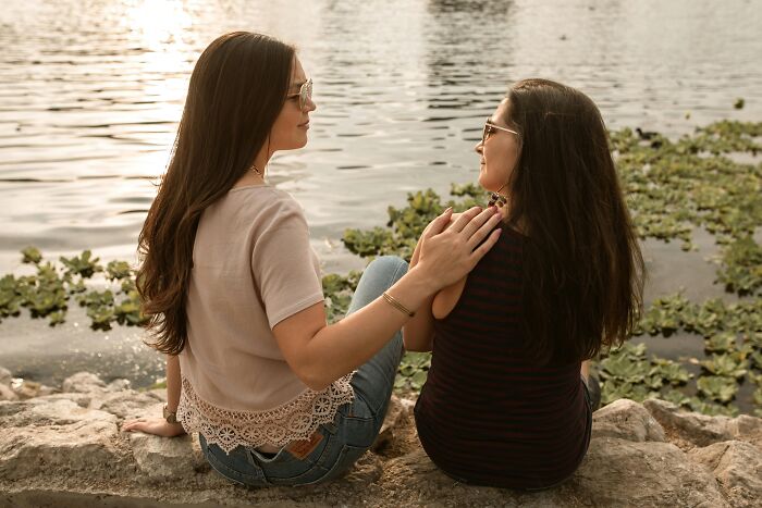 Two women sitting by a lake, enjoying a sunset, symbolizing how life gets noticeably better with simple approaches.