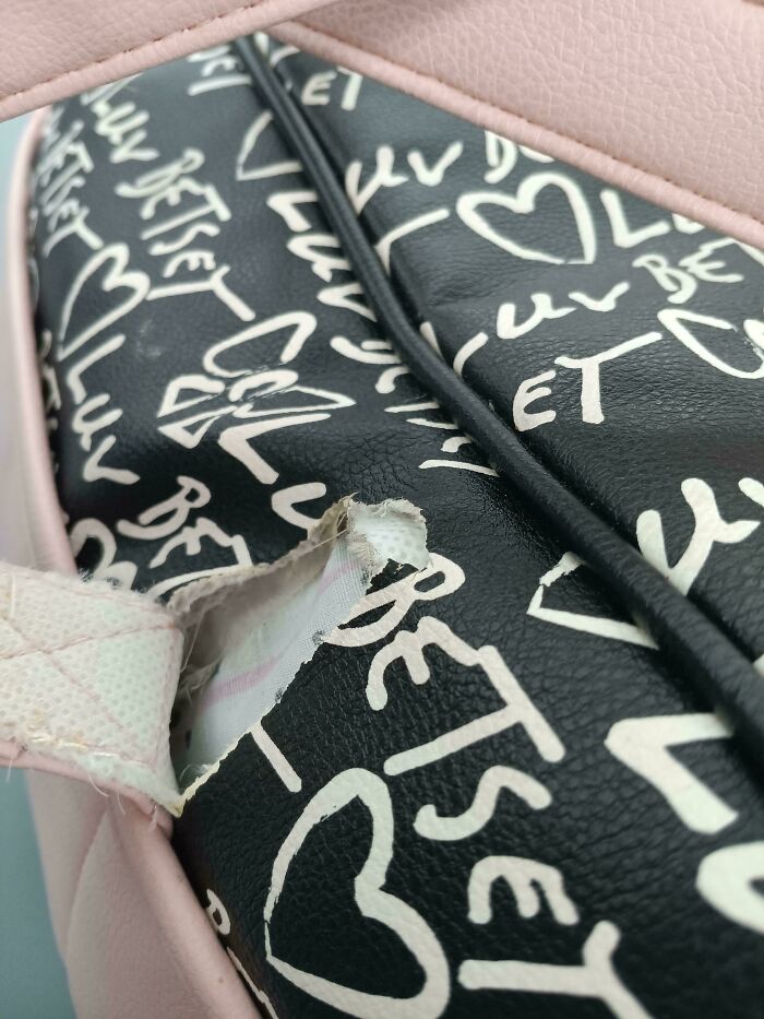 Damaged luggage with a large tear exposing inner lining, showcasing an airline baggage fail.