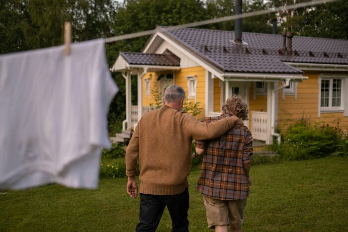 Two people walking towards a yellow house, showcasing simple approaches to improve life.