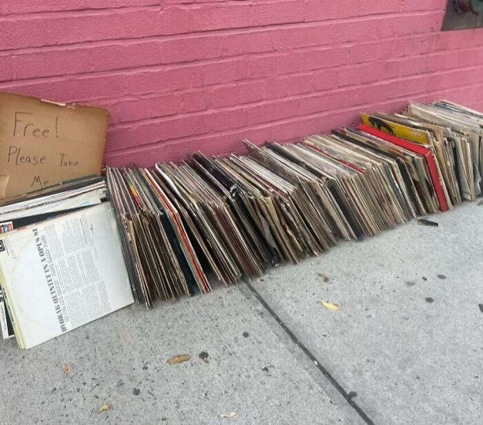 Free records left on a NYC curb, with a "please take me" sign, offering treasures to passersby.