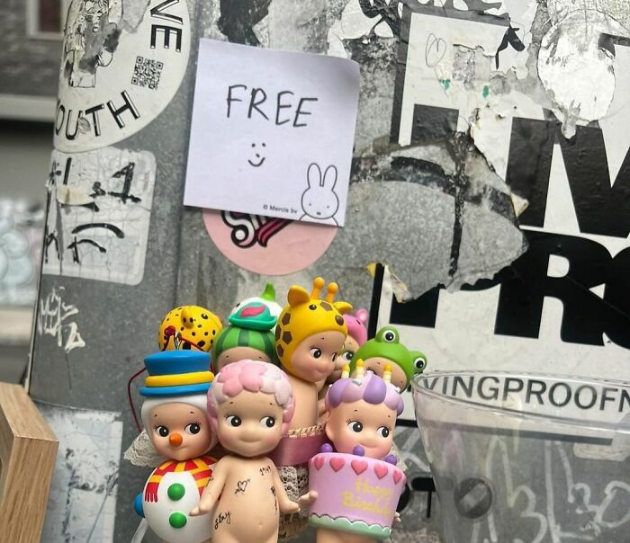Colorful figurines with a "free" sign on a pole, part of the Stooping NYC curbside treasures collection.