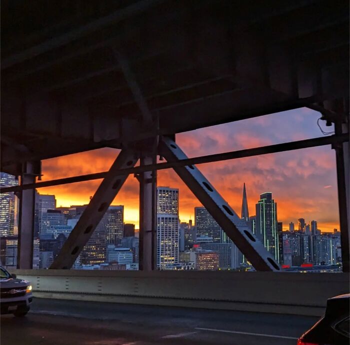 San Francisco skyline at sunset captured by photographer Sage Akaboshi through bridge beams, highlighting city architecture.