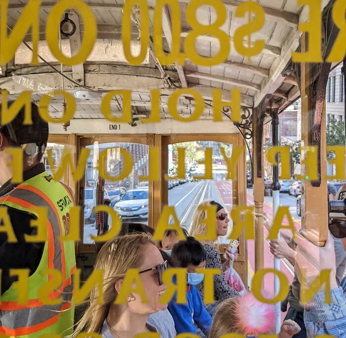 San Francisco cable car interior view with passengers photographed through window text.