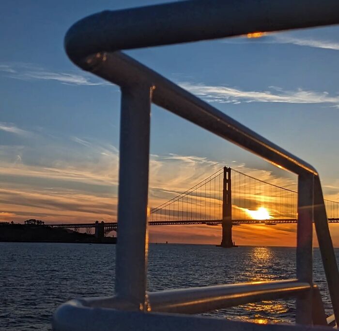 Golden Gate Bridge sunset captured by photographer Sage Akaboshi, viewed through a boat railing.