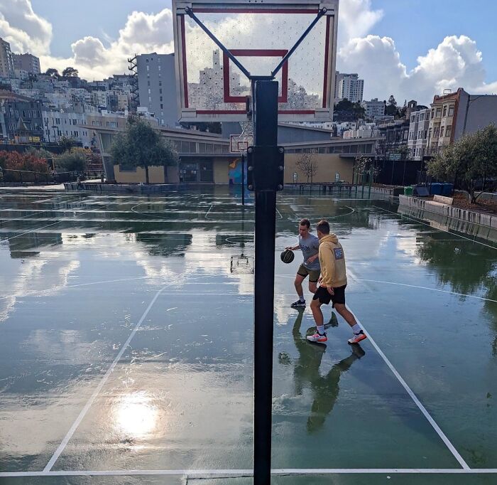 Street basketball scene in San Francisco, capturing urban life and reflections on a wet court through Sage Akaboshi's lens.