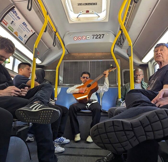 Passengers on a San Francisco bus with a man playing guitar, capturing the city's essence.