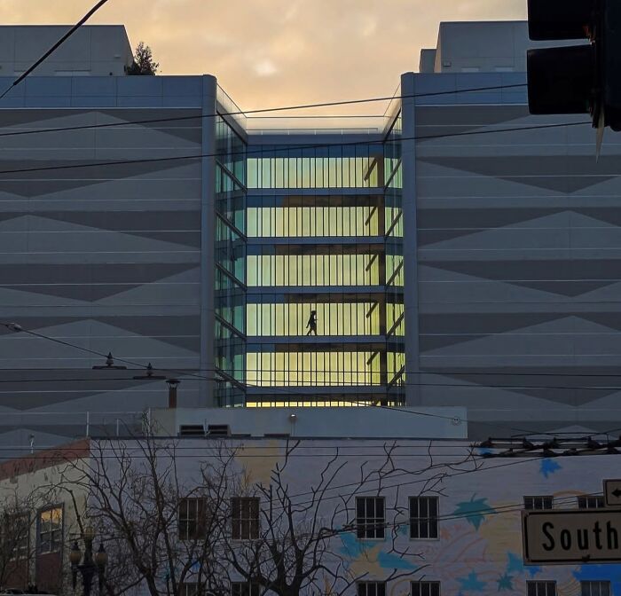 San Francisco building with a silhouette of a person walking on a skywalk at sunset, captured by photographer Sage Akaboshi.